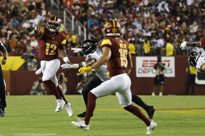Washington Commanders quarterback Jacoby Brissett (12) passes the ball to Commanders wide receiver Dax Milne (15) as Baltimore Ravens linebacker Tavius Robinson (95) chases during the third quarter at FedExField.
